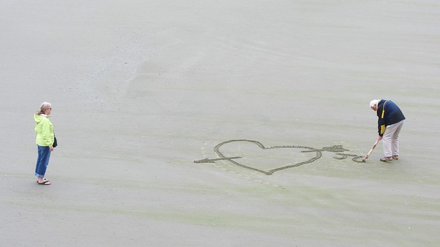 muž kreslící srdce do písku ženě
